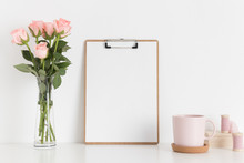 Wooden Clipboard Mockup With A Bouquet Of Pink Roses In A Glass Vase On A White Table. Portrait Orientation.