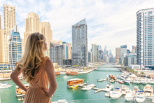 Woman In Dubai Marina, United Arab Emirates. Attractive Lady Wearing A Long Dress Admiring Marina Daylight Views