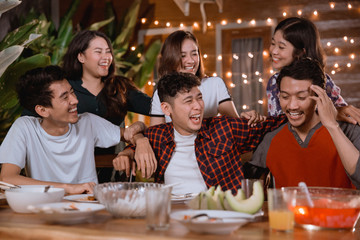 Wall Mural - fun young people laughing while having garden party at home and having some dinner