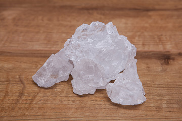 Coarse granules of natural rock or sea salt on a rustic old wooden table.