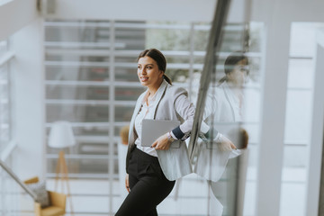 Young business woman stands on the stairs at the office and use mobile phone