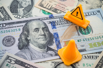 Wall Mural - Traffic cone and dangerous under construction warning sign area on US dollar banknotes bill background. Concept of fix, repair, USA or global world economy financial crisis solution, personal loan.