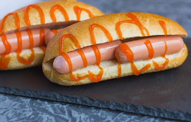 fresh hot dogs with sharp ketchup on a stone Board