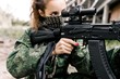 Armed woman in camouflage holding a sniper rifle aims at the target