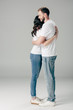 © LIGHTFIELD STUDIOS - happy young couple in white t-shirts and blue jeans embracing on grey background