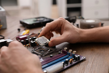 Male technician repairing motherboard at table, closeup