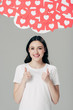 © LIGHTFIELD STUDIOS - cheerful pretty girl in white t-shirt showing thumbs up near red paper cut cards with hearts symbols isolated on grey