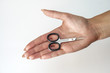 © subjob - Manicure scissors on the hand of a young girl. Female beauty and body care. Stock photo