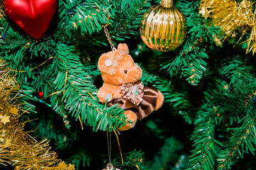 Christmas tree decorated with Christmas toys: a golden ball, a red heart and a teddy bear