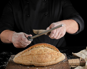 Wall Mural - chef in black uniform sharpens a kitchen knife