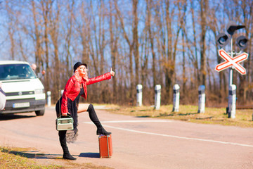  Beautiful young woman catching a car hitchhiking along the road