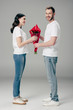 © LIGHTFIELD STUDIOS - handsome young man gifting bouquet of red roses to pretty girlfriend on grey background