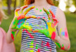 the girl with the hands smeared with colored fingers shows the heart on the background of nature and the sun