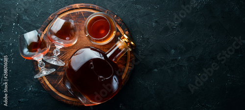 Cuadros en Lienzo A bottle of cognac and glasses on a black background