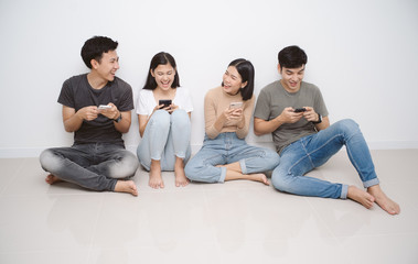 Group of friends sitting on the floor using smart mobile phones. People addiction to new technology trends. Concept of youth, z generation, social network and friendship.