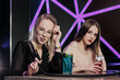 © spaskov - Two young smart beautiful girls in dresses sit at a table in a nightclub or hookah. They smoke hookah and smoke and drink cocktails from glasses with tubules, talk and laugh.