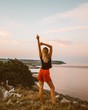 © Roberta Weislogel/Scopio - woman in black sleeveless top with red short shorts standing on hill near body of water