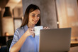 © JustLife - Businesswoman holding hot drink and using laptop