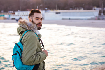 Wall Mural - Stylish young man with backpack near sea