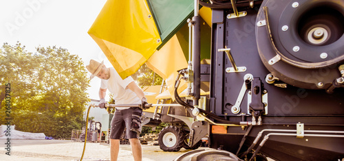 Cuadros en Lienzo The mechanics repair the yellow and green combine harvester in the farm yard