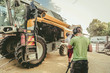 © karepa - The mechanics repair the yellow and green combine harvester in the farm yard.