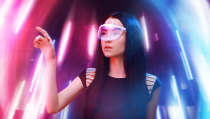 Beautiful woman in futuristic 3d glasses with virtual projection over neon light background. Girl in glasses of virtual reality. Augmented reality, science, future technology, robots concept. VR.