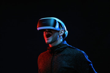 Model young man with beard in glasses of virtual reality on dark background.. Augmented reality, science, future technology concept. VR. Futuristic 3d glasses with virtual projection. Neon light.