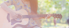 Woman Hand Is Playing Acoustic Guitar In The Garden.
