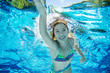 Child swims underwater in swimming pool, happy active teenager girl dives and has fun under water, kid fitness and sport on family vacation on resort