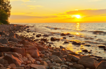 Wall Mural - Beautiful sunset on the coast of Baikal Lake. Pink solar reflections in the waves. Summer seascape of stony beach
