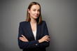 © luengo_ua - Confident young business woman in suit looking at camera. Grey background with copy space.
