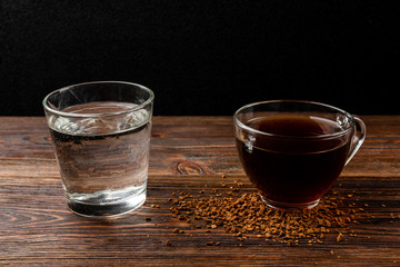 Cup of  coffee and water on dark wooden background.