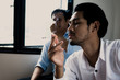 © khwanchai - World No Tobacco Day in May, stop smoking and against  concept, young man choking of smoke  as sitting near people holding cigarette in dark tone