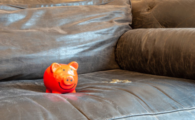 piggy bank on a couch - concept image saving money at home