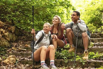 Wall Mural - group of hikers taking a break after long walk in nature.they sitting on old path stairs.