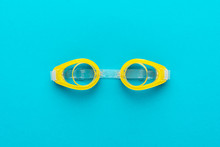 Flat Lay Shot Of Yellow Swimming Goggles Over Turquoise Blue Background. Minimalist Photo Of Swimming Goggles With Central Composition