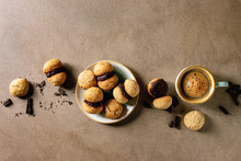 Baci Di Dama Homemade Italian Hazelnut Biscuits Cookies With Chocolate Cream Served In Ceramic Plate With Cup Of Espresso Coffee Over Brown Texture Background. Flat Lay, Space