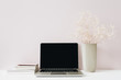 Minimalist home office desk workspace with laptop, flowers bouquet on pink background. Front view hero header with blank copy space.