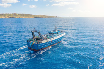 Wall Mural - Fishing vessel boat floating in the blue sea along the coast.