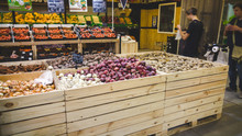 Closeup Image Of Garlic, Onions, Potatoes And Other Fresh Vegetables Lying In Wooden Crated In Grocery Store