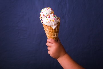 Canvas Print - A child's hand holding a tasty delicious ice cream cone