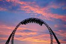 Silhouette Of People Having Fun On A Roller-coaster In An Amusement Park At Sunset. Adrenalin Concept.