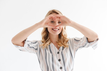 Sticker - Portrait of positive blond woman smiling at camera while showing heart shape with fingers