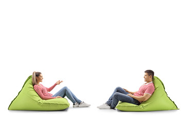 Sticker - Casual young man and woman sitting on bean bags having a conversation