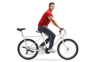 Wall Mural - Young cheerful man riding a tandem bicycle alone and smiling at the camera