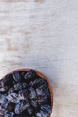 Wall Mural - Dark blue raisins in a wooden bowl on a bright white background. Close-up. Insulated.