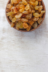 Sticker - Light yellow raisins in a wooden bowl on a light white background. Close-up. Isolated.