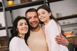 © LIGHTFIELD STUDIOS - happy man hugging attractive wife and cute daughter at home