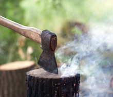 Axe In Tree Stump And Campfire With Smoke In Summer Forest