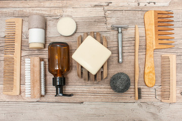 Zero waste bathroom accessories, metal safety razor, wooden comb, deodorant, shea butter, solid soap and shampoo, toothbrush, olive oil make up remover in a glass container, nail brush. Flat lay.